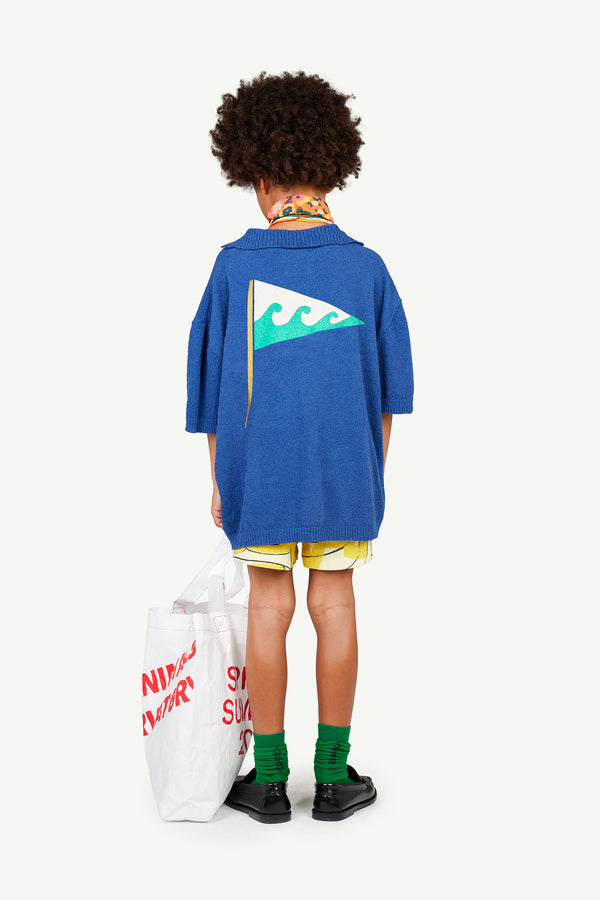 A kid in a total look from The Animals Observatory seen from the back. In this image, they are wearing the Navy Raven Knitted Polo Shirt, Green Worm Socks, and White Pack Iguana Necklace.